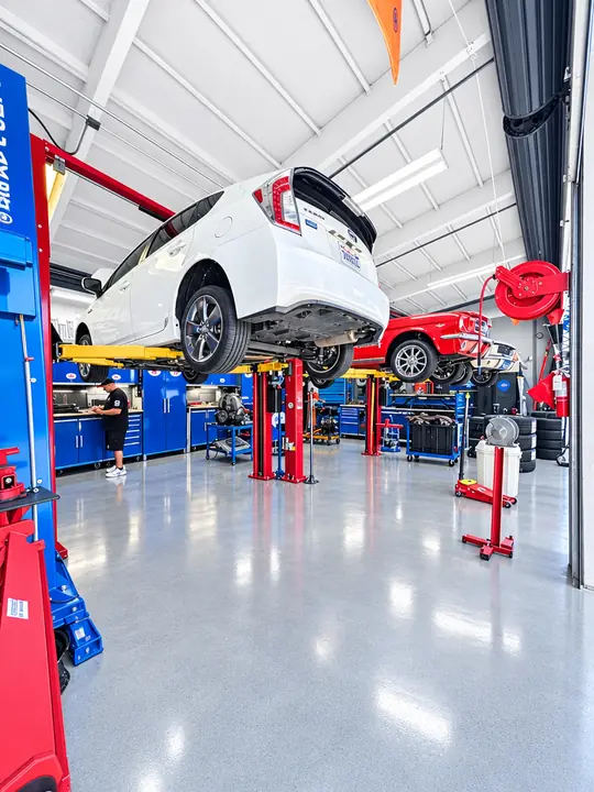 Service bays with vehicle lifts and a clean epoxy floor at Cedillo's auto repair in Fullerton
