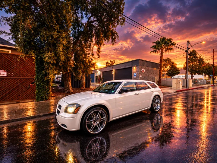 White Dodge Magnum with chrome wheels reflecting on a wet street outside Cedillo's in Fullerton