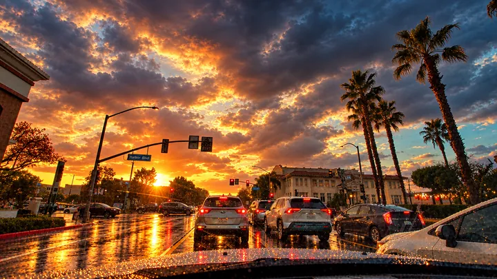 Wet intersection at Harbor Blvd in Fullerton at sunset, with cars waiting at the light and storm clouds overhead
