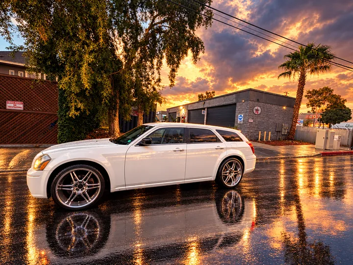 White Dodge Magnum wagon on wet pavement near Cedillo's auto repair shop in Fullerton at sunset