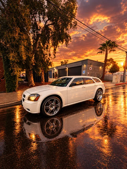White Dodge Magnum reflected in rainwater at sunset near Cedillo's auto repair in Fullerton